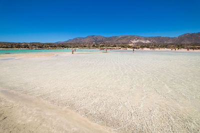 Scenic view of beach against clear blue sky