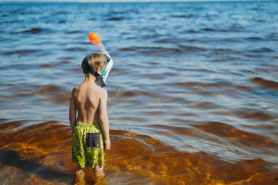 Cute little caucasian boy wearing snorkeling mask going to swim in the sea