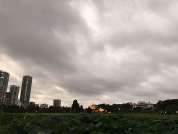 Buildings in city against storm clouds