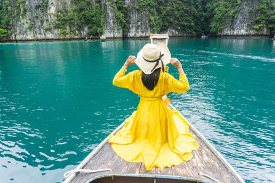Rear view of woman standing against yellow water
