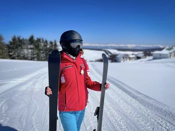 Selective focus of woman skier standing on the slope and holding her skis in a vertical position