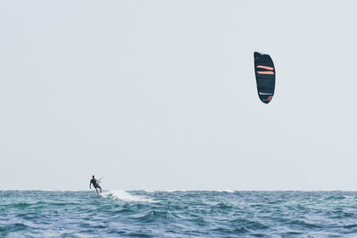 Man paragliding in sea against clear sky