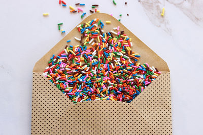 Directly above shot of sprinkles in paper envelope on white background