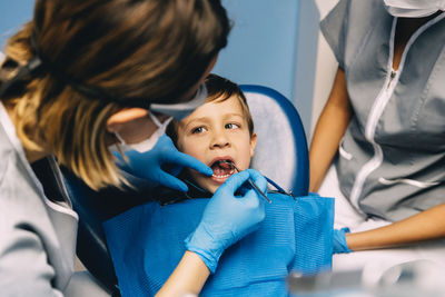 Dentist operating boy in medical clinic