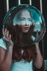 Close-up of thoughtful young woman wearing glass helmet in head against metallic railing