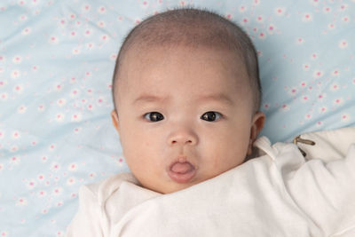 Portrait of cute baby lying on bed