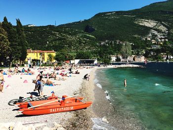 People on shore by mountains against sky