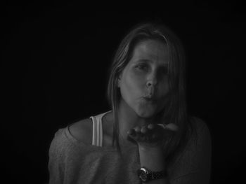 Portrait of woman blowing kiss over black background