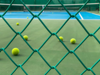 The blur of the tennis ball on the tennis court looking over the green iron net