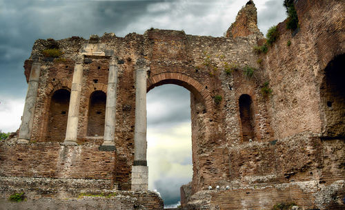 Low angle view of old ruin building against cloudy sky