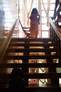 Rear view of woman sitting on staircase