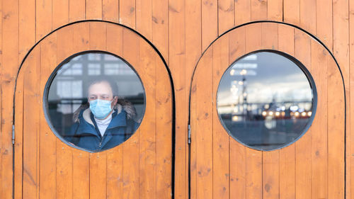 Man wearing mask looking through window