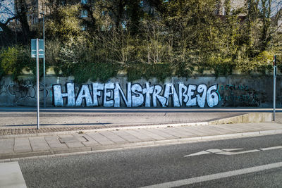 Text on road against trees in city