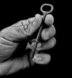 Close-up of man holding hand over black background