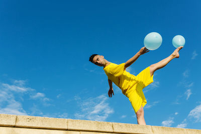 Low angle view of man playing against blue sky