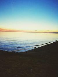 Silhouette man on beach against clear sky during sunset