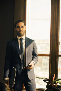 Portrait of legal advisor standing by window at law office