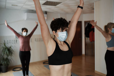 Group of women practicing pilates exercises in class with masks