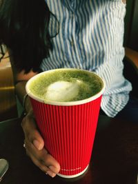 Midsection of woman holding drink on table