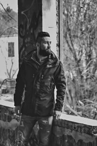 Young man looking away standing in abandoned built structure