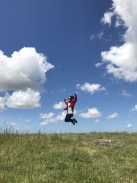 Man jumping on field against sky