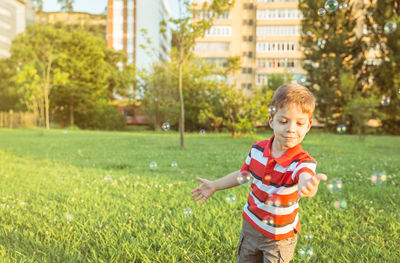 Boy on grass against trees