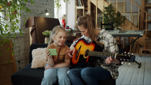 Mother teaching guitar to daughter