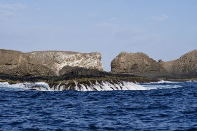 Rock formations in sea against blue sky