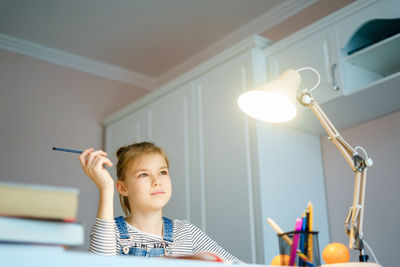 Portrait of happy boy holding illuminated lamp at home