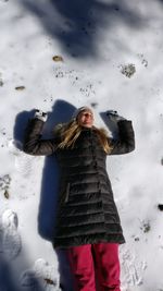 High angle view of young woman lying on snowfield