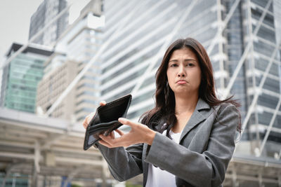 Businesswoman with empty wallet in city
