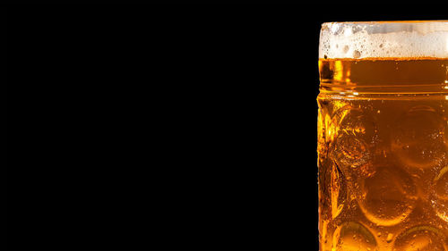 Close-up of beer glass against black background