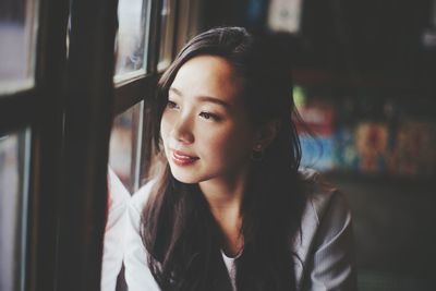 Portrait of young woman looking through window