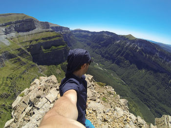 Midsection of man looking at mountain range against sky