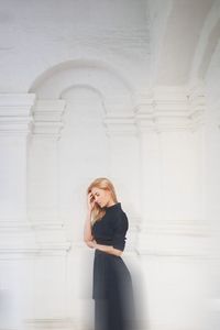 Young woman standing against wall