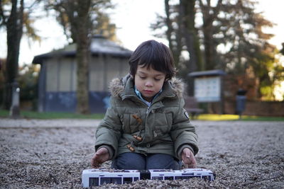 Cute boy sitting in park during winter