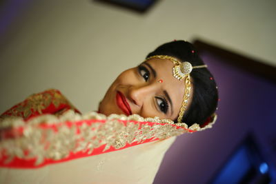 Close-up of smiling bride wearing maang tikka and sari