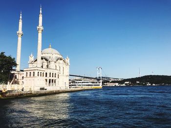 View of building by river against blue sky