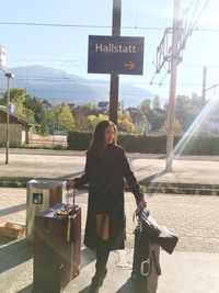 Full length of woman standing by sign