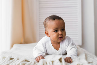 Portrait of cute baby on bed at home