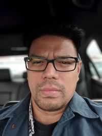 Portrait of man wearing eyeglasses sitting in car 