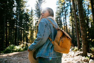 Midsection of woman standing by tree in forest