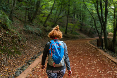 Rear view of woman walking on road in forest