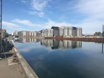 Buildings by river against sky in city