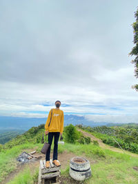 Rear view of man standing on landscape against sky