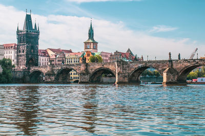 Arch bridge over river against buildings in city