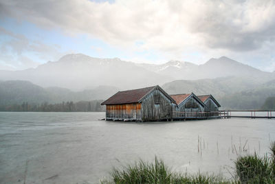 House by lake and mountains against sky