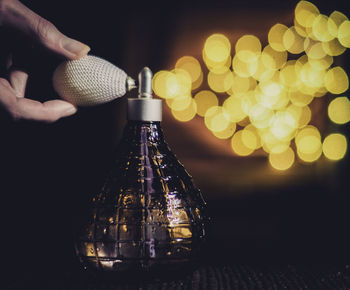 Close-up of hand holding illuminated bottle