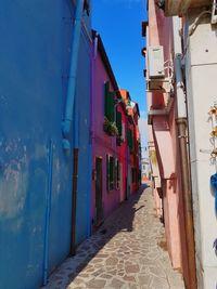 Alley amidst buildings against blue sky