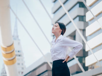 Smiling young woman with hand on hip standing in city